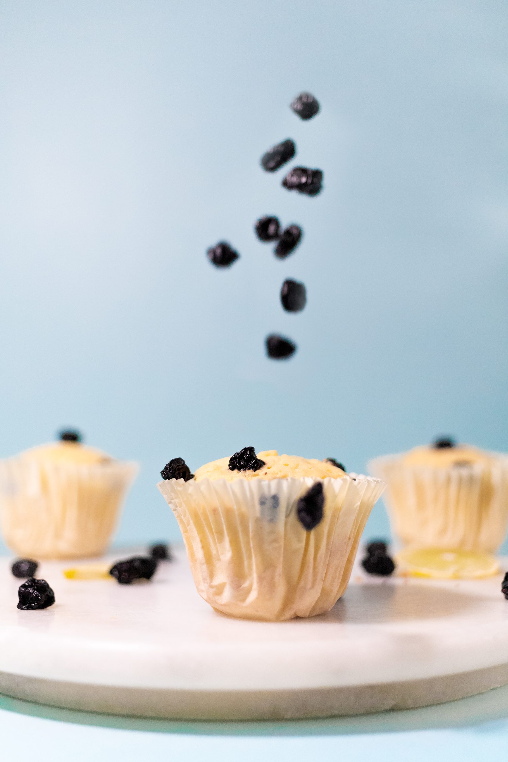 Cupcakes on a marble slab with berries falling into frame