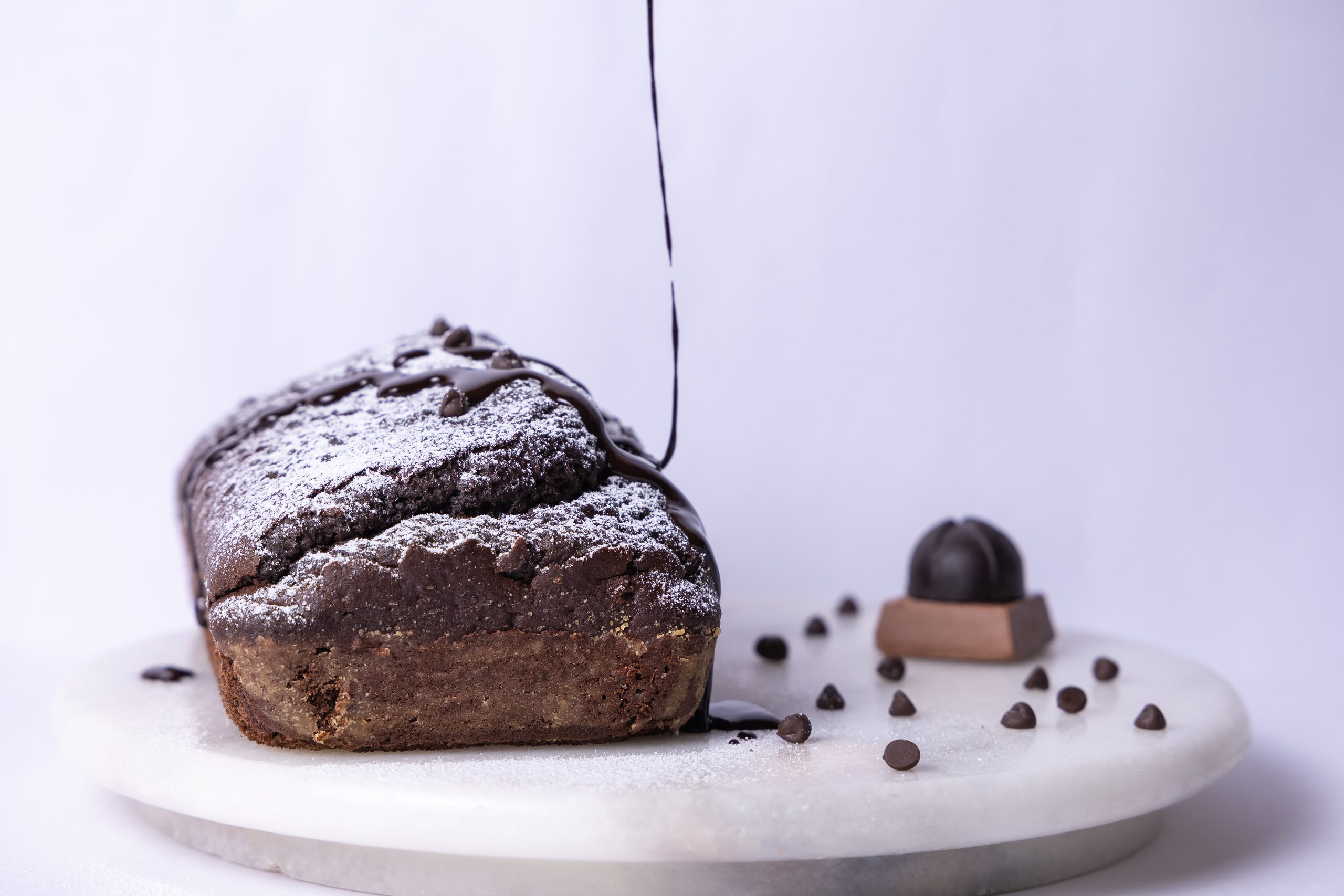 Chocolate loaf with chocolate drizzle on a marble plate