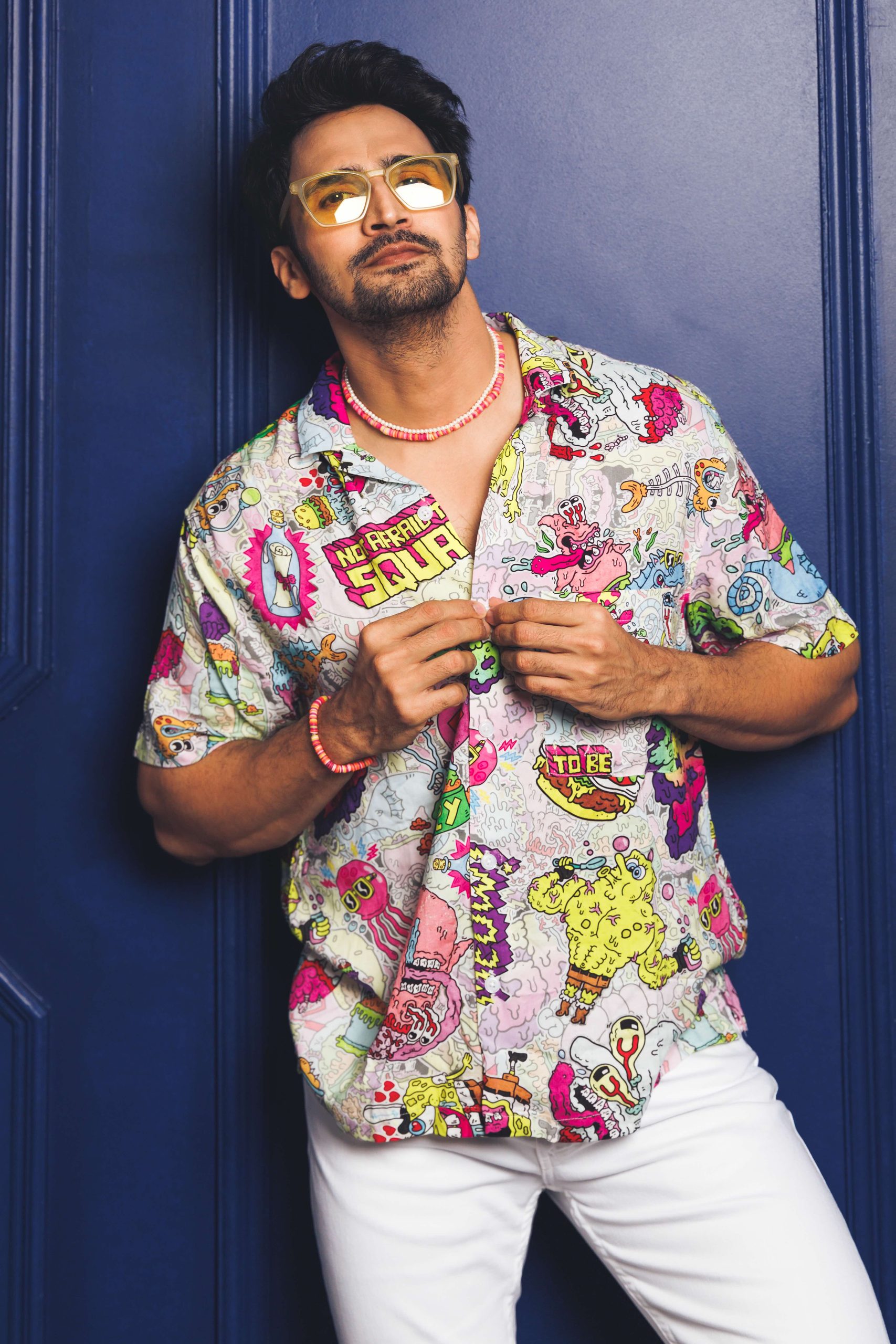 Model in a patterned shirt leaning against a blue door